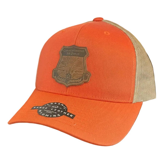An orange and beige trucker cap with a dark brown shield patch on the front.