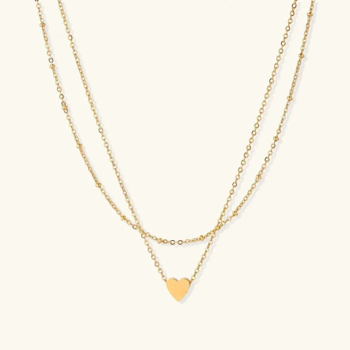 Layered Heart Necklace in gold-tone metal with two delicate chains, one beaded, and a small polished heart pendant.